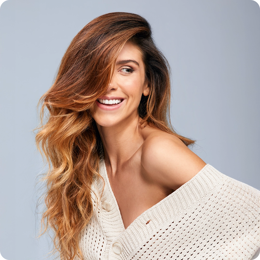 Frau mit langem, gewelltem Haar in Karamell-Balayage – Emsibeth THERMAL Haarpflege
